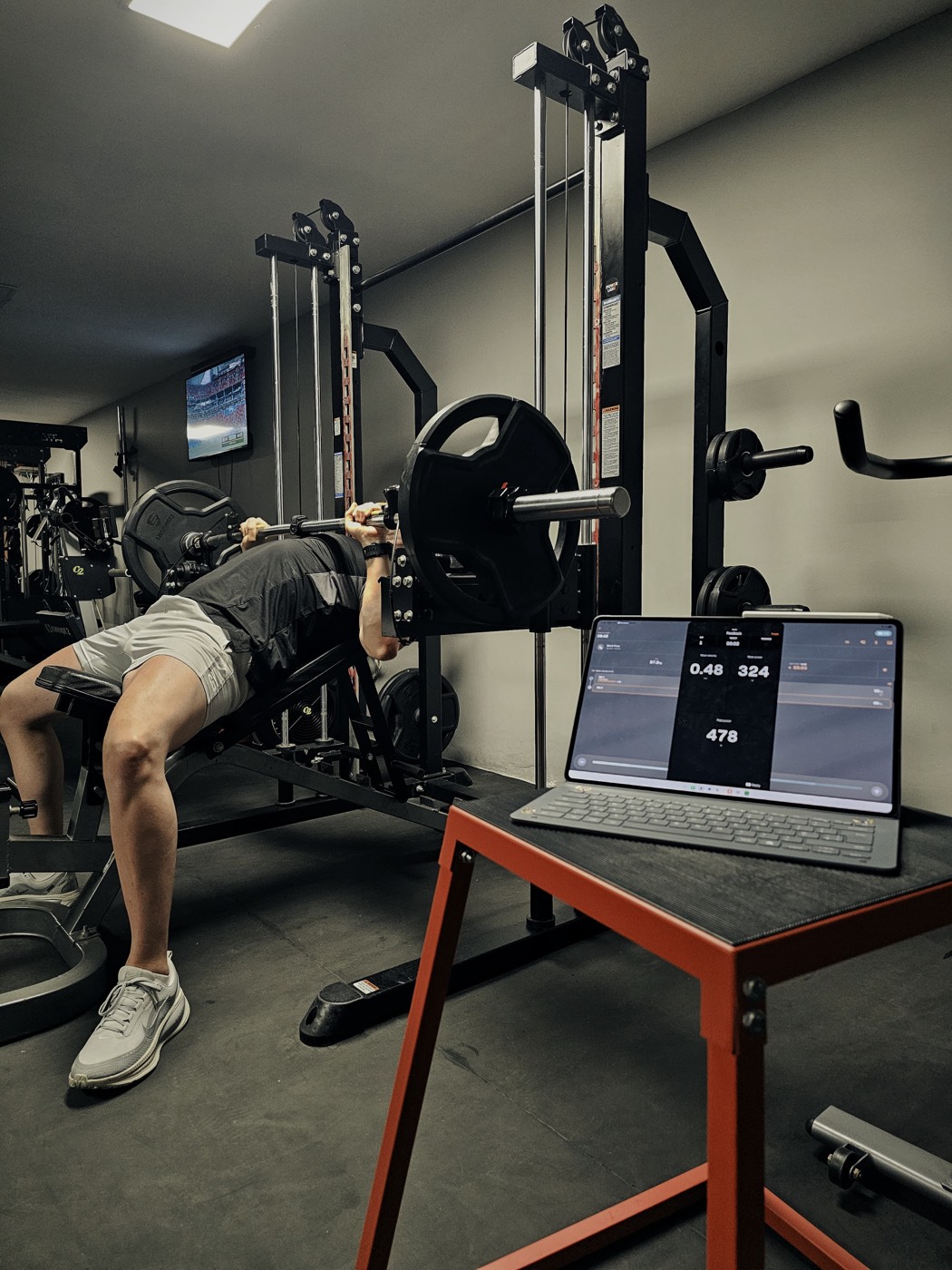 Fighter bench pressing while a tablet tracks bar speed and power output live